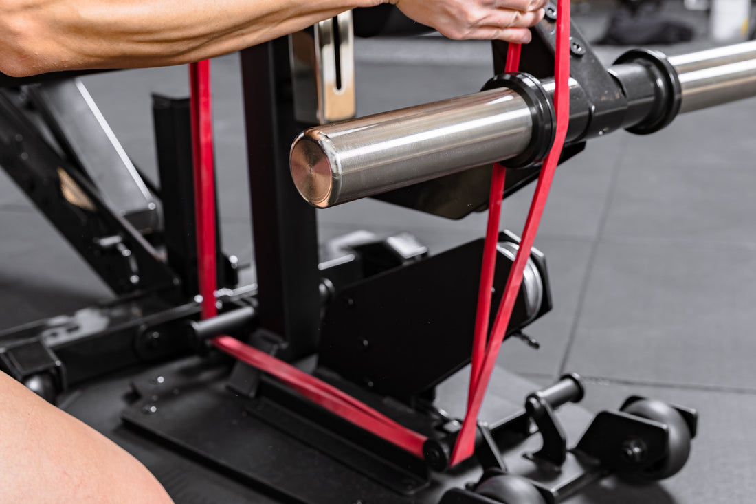 Athlete loading a resistance band onto the Leg Extension & Leg Curl Bench Attachment