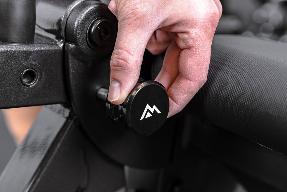 Athlete removing the storage pin on the Leg Extension & Leg Curl Bench Attachment