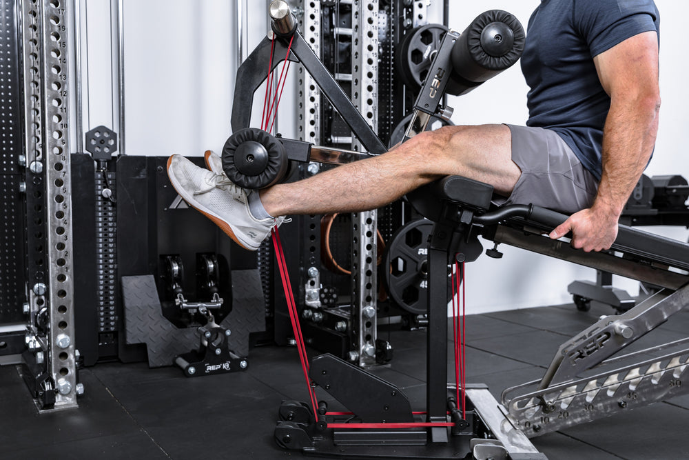 Athlete using resistance bands to do leg extensions on the Leg Extension & Leg Curl Bench Attachment