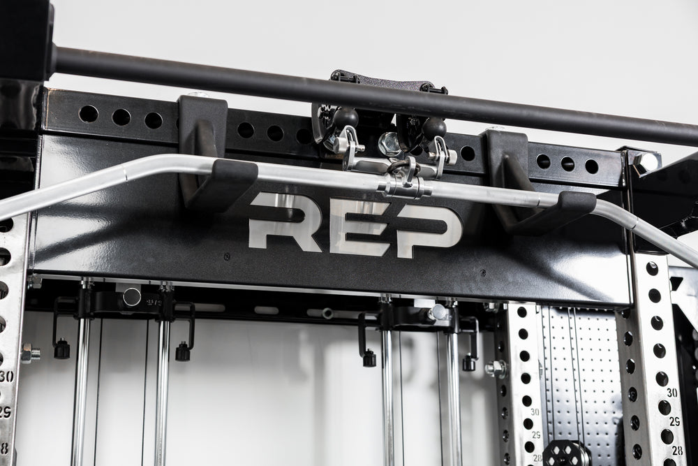 Close-up of 1.25" pull-up bar with Logo Plate Crossmember 2.0 - Standard - 'REP' branding on a gym rack.