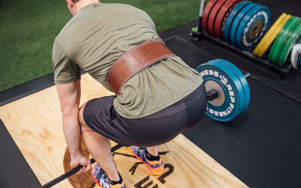 Back view of an athlete setting up to perform a deadlift while wearing a brown REP Leather Olympic Lifting Belt.