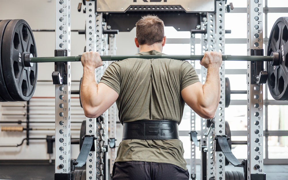 Back view of an athlete at the top of a back squat while wearing a black REP Leather Olympic Lifting Belt.