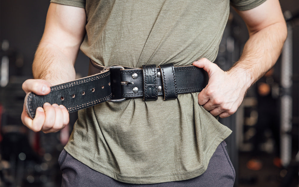 Close-up front view of athlete putting on the black REP Leather Olympic Lifting Belt.