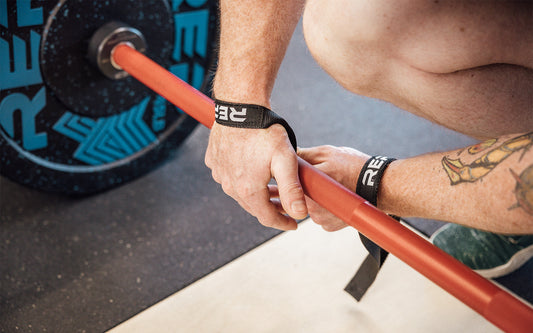 Accessories - A close up of someone putting on REP® branded wrist wraps for a barbell exercise.