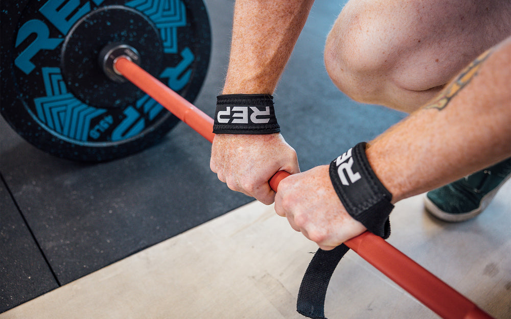 Lifter securing his REP Lifting Strap to a barbell.