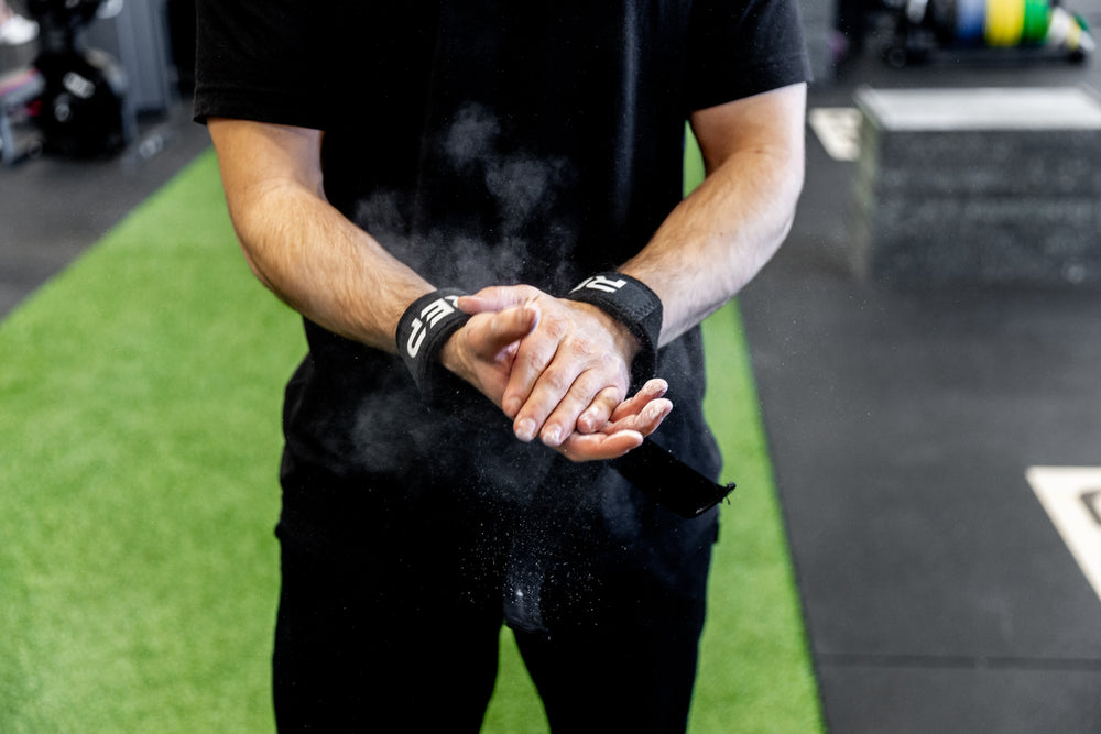 Lifter applying chalk to his hand wile wearing REP Lifting Straps.