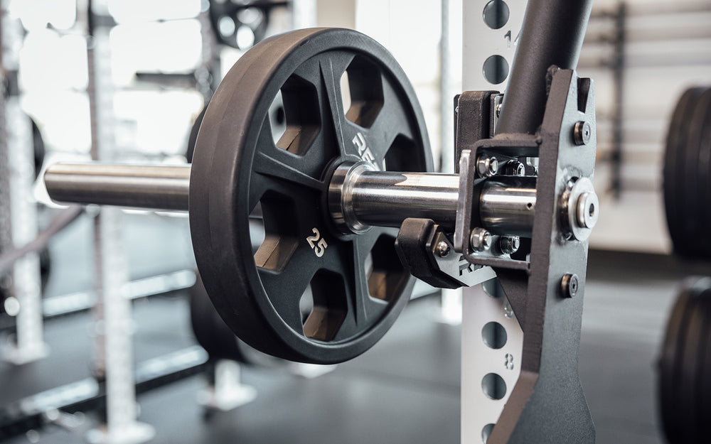 Close up of a racked REP Open Trap Bar sleeve with a 25lb plate loaded.