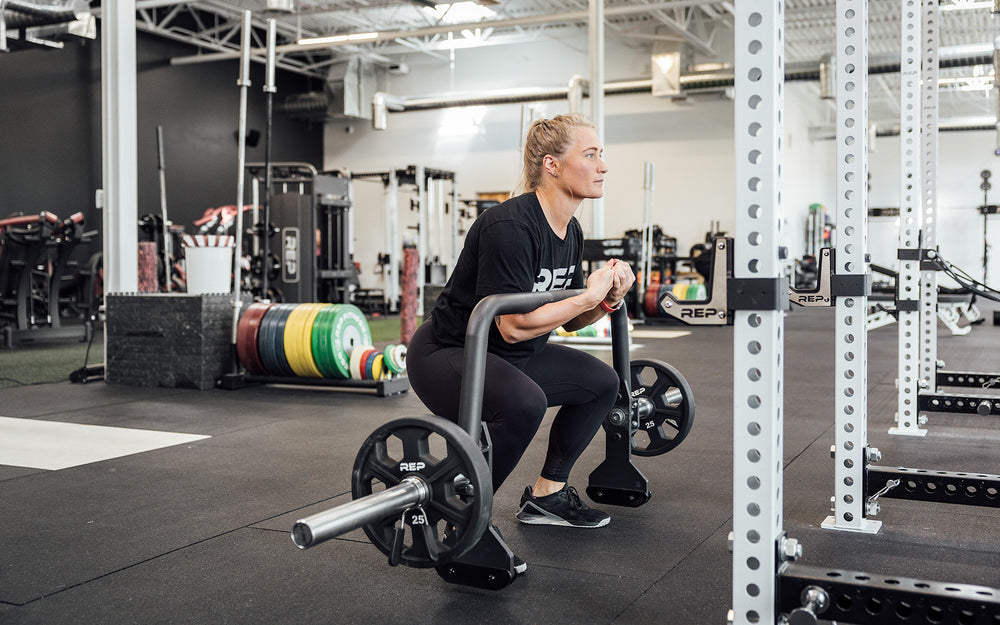 Female athlete performing a zercher squat with the REP Open Trap Bar.