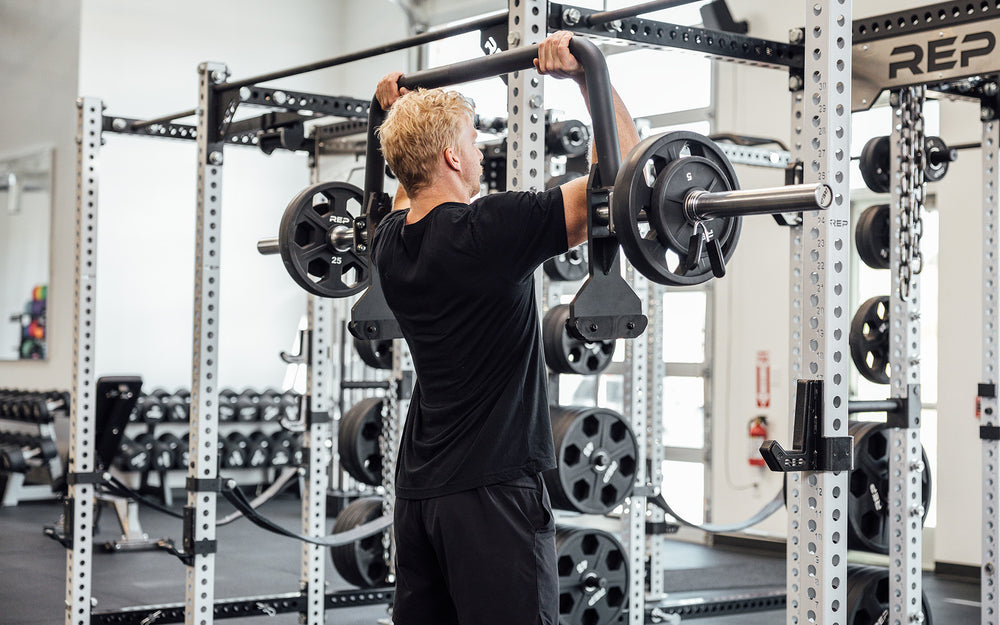 Male athlete performing an overhead press with the REP Open Trap Bar.