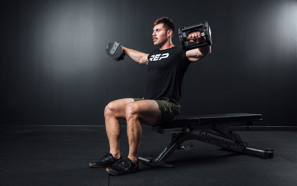 Athlete performing seated lateral shoulder raises with a pair of REP x PÉPIN FAST Series Adjustable Dumbbells.