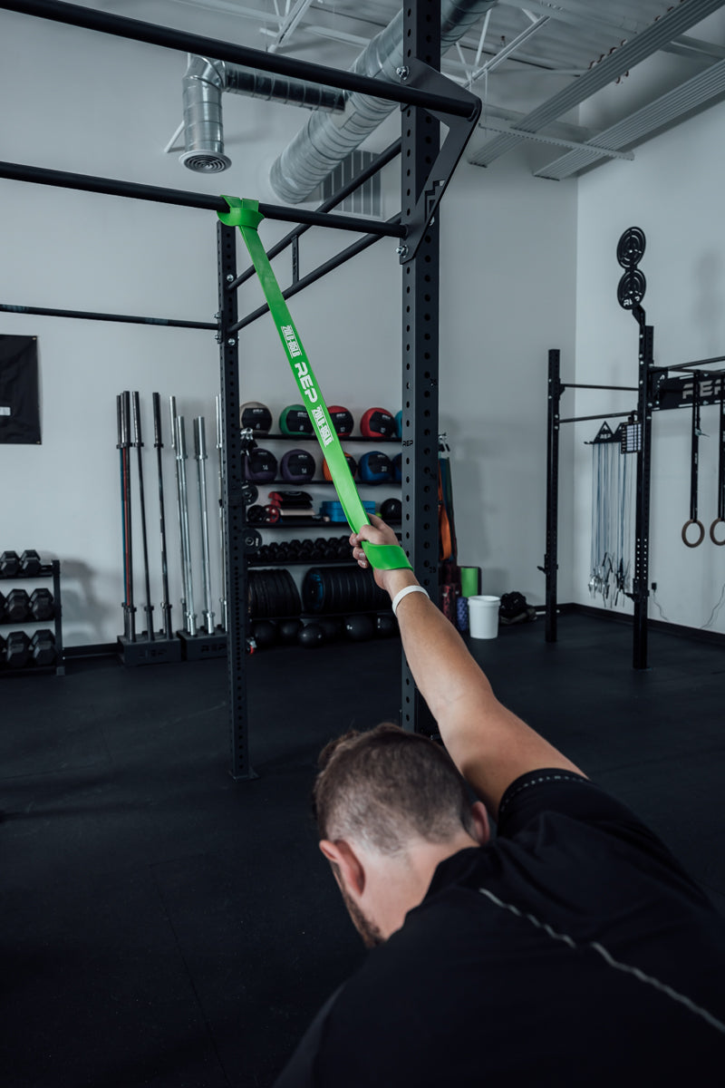 Athlete stretching with a green Latex-Free Pull-Up Band.