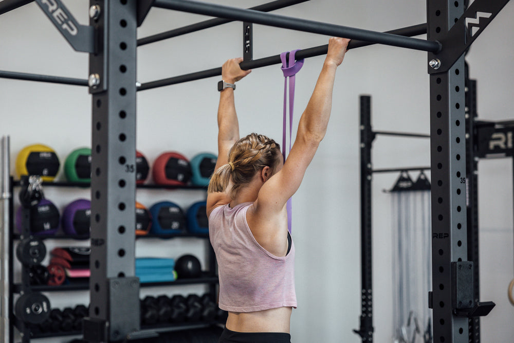 Athlete using a purple Latex-Free Pull-Up Band for assistance while performing pull-ups.