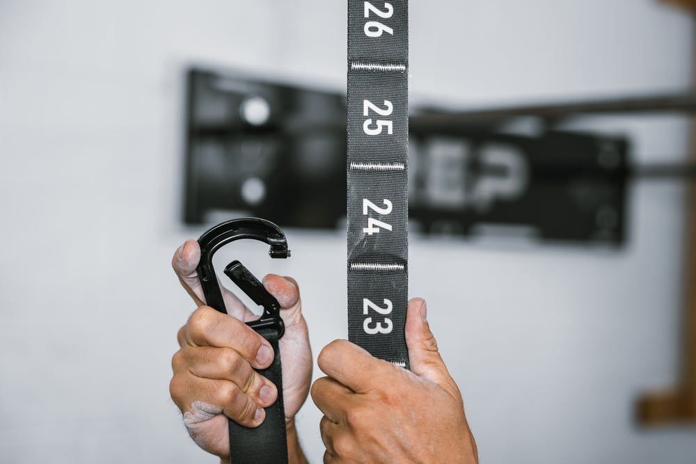 Athlete using the locking carabiner to attach the REP Competition Gymnastic Strap to a numbered adjustment section
