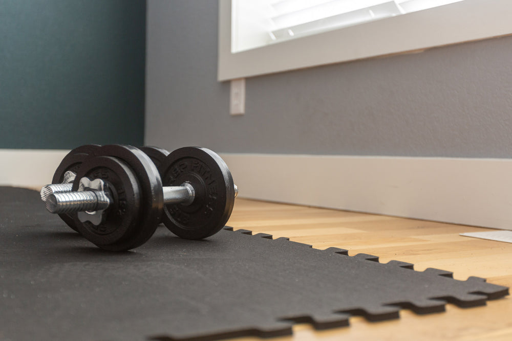 Adjustable dumbbells on top of Rubber Floor Tiles on a wood floor