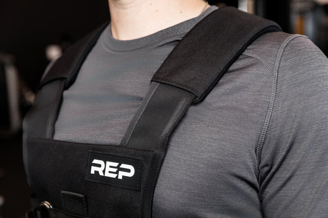 Person wearing black Sled Harness with 'REP' branding in a gym setting