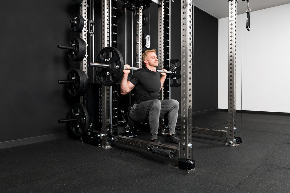 Athlete doing squats on a smith machine inside a rack built with stainless steel crossmembers