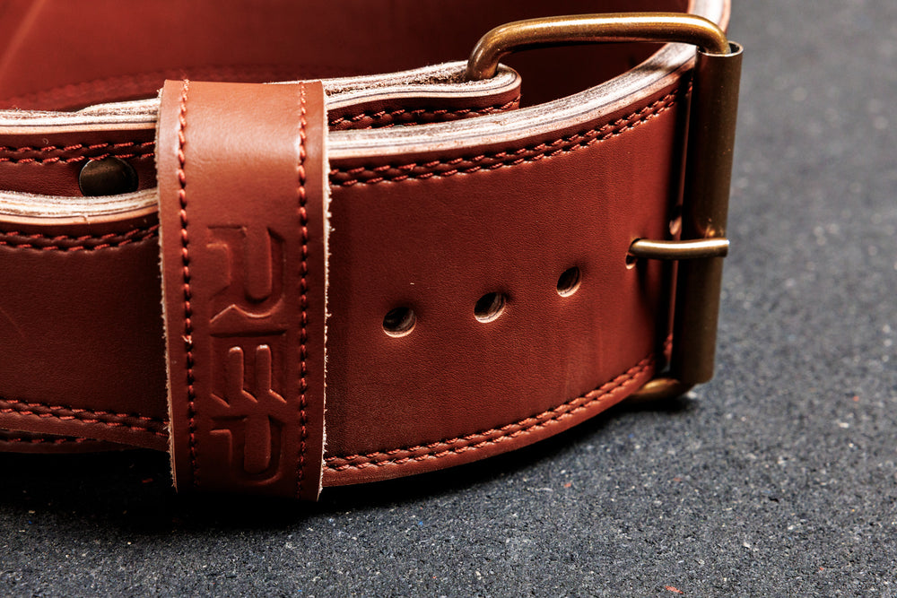 Close-up shot: REP Leather Lifting Belt in brown shows the detail of the debossed REP branding on the belt loop