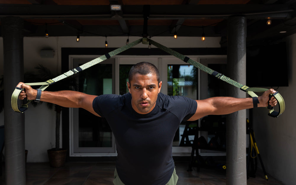 Action shot: Athlete using the TRX® Pro4 Suspension Trainer in Camo to perform a chest fly exercise