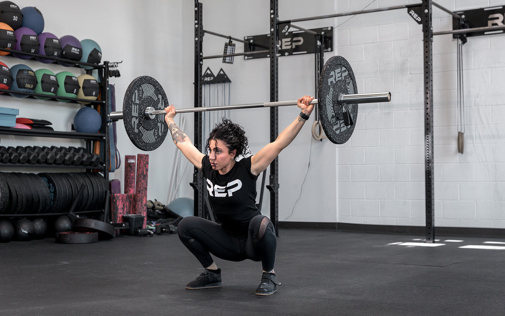 Athlete in the bottom of a snatch using the REP 15kg Teton Training Bar.