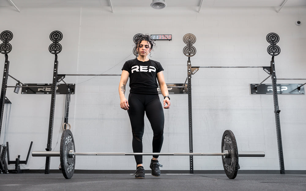 Athlete walking up to a loaded REP 15kg Teton Training Bar on the gound.