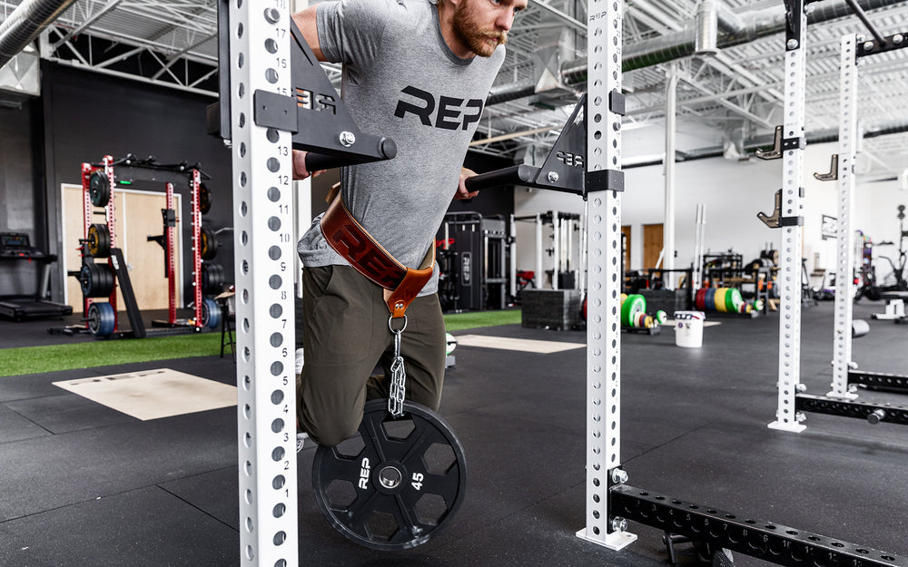 Athlete is performing a weighted dip using the REP Leather Utility Loop.