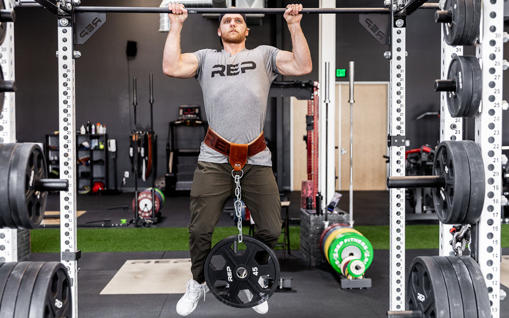 Athlete is performing a weighted pull-up using the REP Leather Utility Loop.