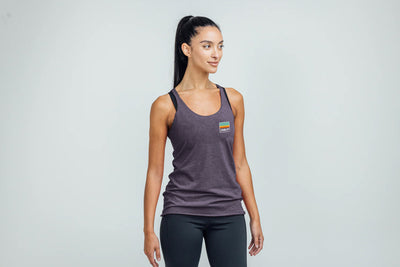 Woman wearing a Rise Tri-Blend Tank in purple with a logo on a gray background