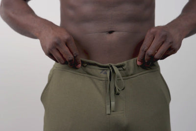 Close-up video of an athlete putting their phone into the zipper pocket on the green Men's Attis Joggers