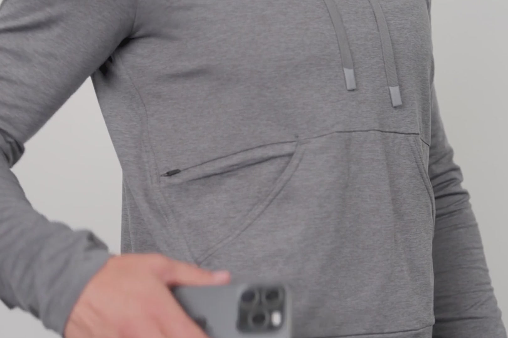 A video of an athlete zipper their phone in the pocket of the Women's Vellus Hoodie