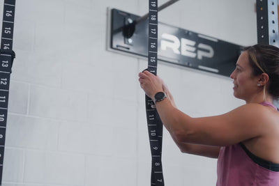 An athlete locking the carabiner to the numbered adjustment sections of the REP Competition Gymnastic Straps and Wood Rings