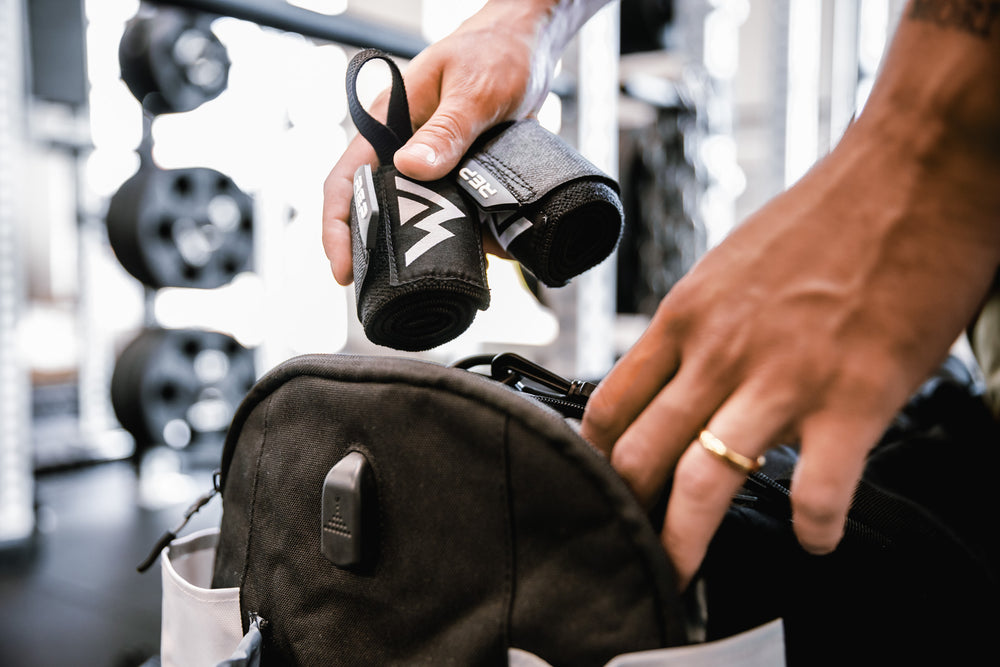 Close up shot of an athlete putting their REP Wrist Wraps into a side pocket of their duffel bag