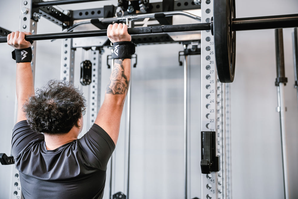 Back shot of an athlete's wrists being supported by the REP Wrist Wraps while pressing a loaded barbell