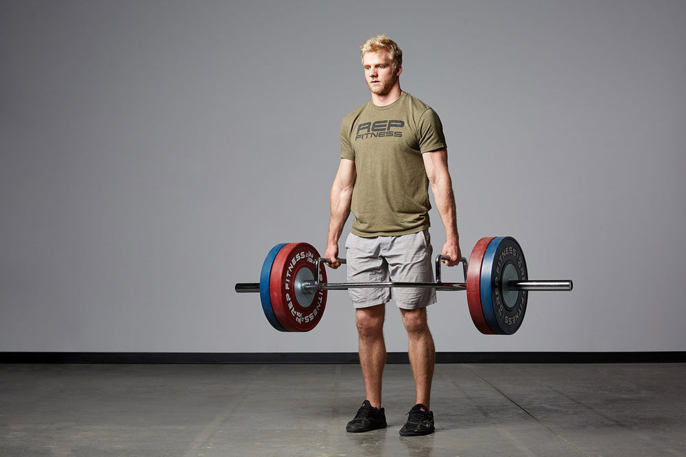 Lifter at the top of a deadlift using a loaded Trap Bar.