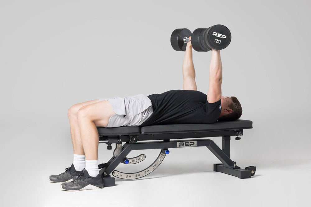 Lifter performing a bench press on an AB-5000 bench with a pair of 70lb Urethane Dumbbells.