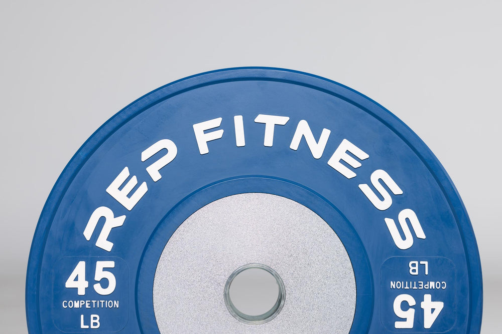 Close-up view of half of a blue 45lb competition bumper plate showing zinc-coated steel disc insert and raised white "REP FITNESS" and weight marking lettering.