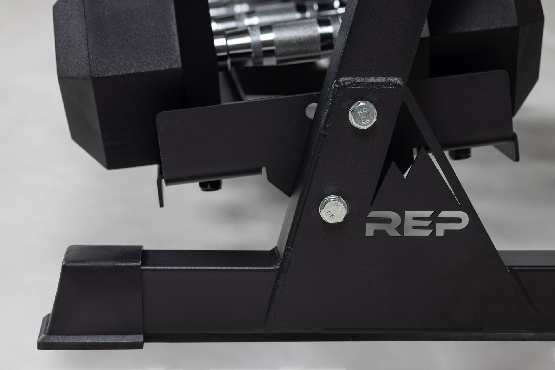 Close-up side view of the bottom of a REP Dumbbell Rack  storing a set of Ergo Hex Dumbbells.