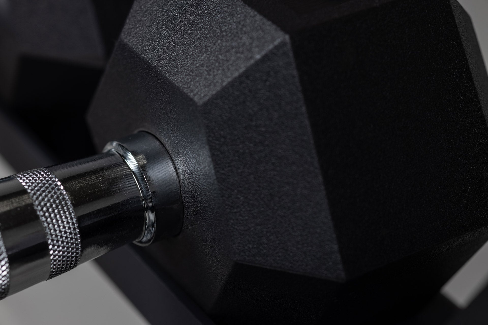Close-up view of the chrome ergonomic handle meeting the rubber-coated hexagon head of a REP Ergo Hex Dumbbell.