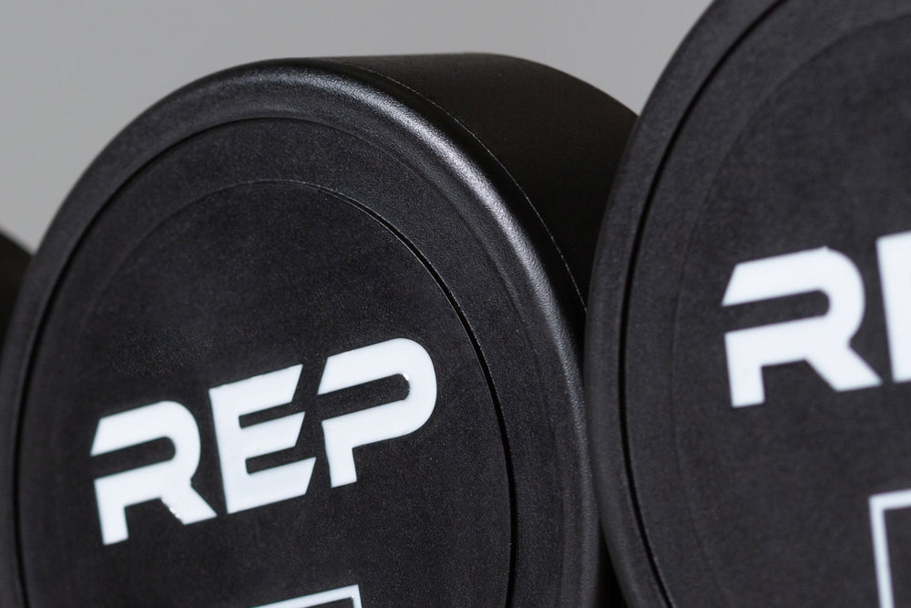 Close-up view of the round head and white "REP" logo of a Urethane Dumbbell.