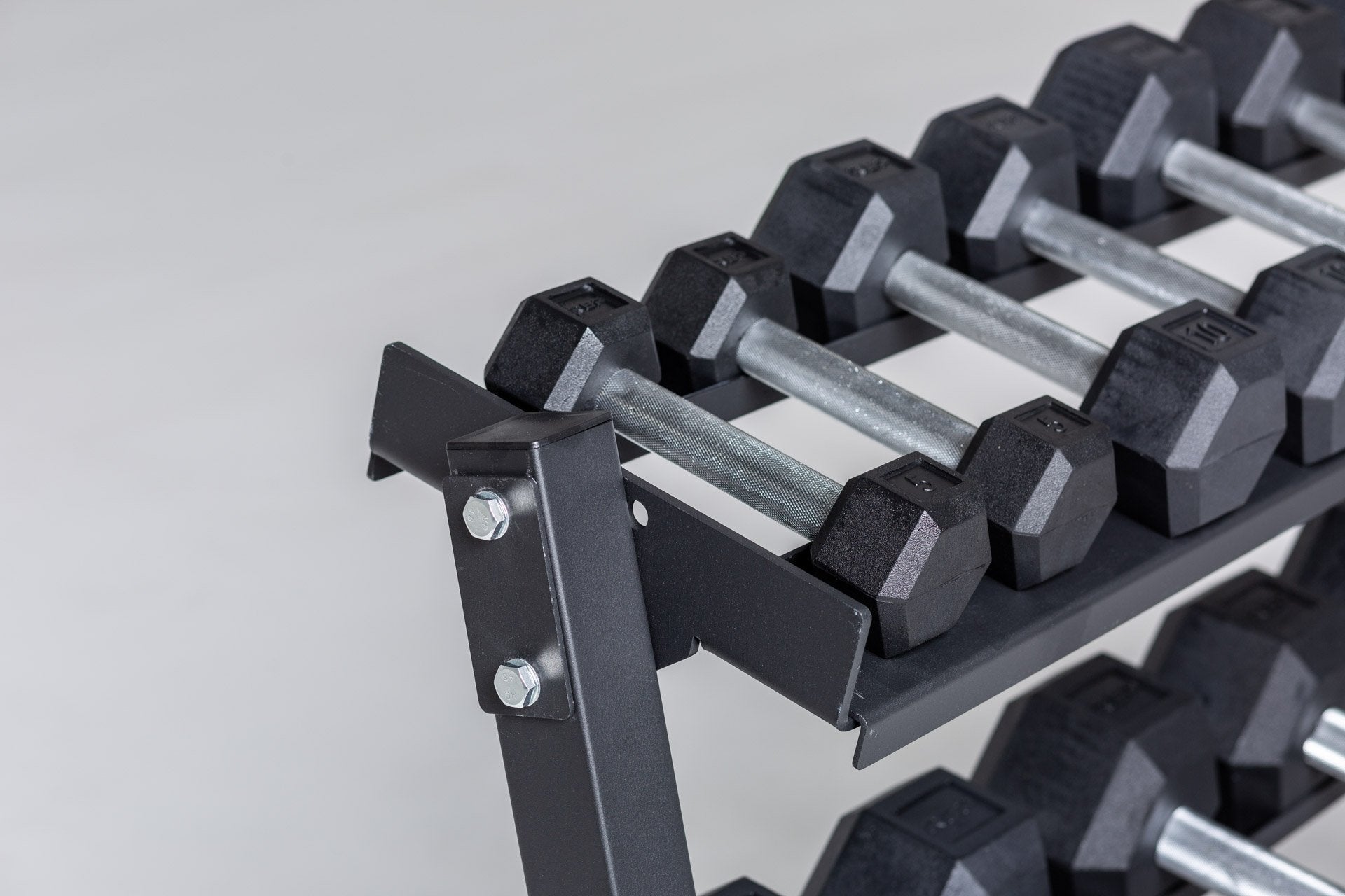 Close-up view of the 5 and 10lb pairs of a 5-50lb Hex Dumbbell Set being stored on the top shelf of a REP Dumbbell Rack.