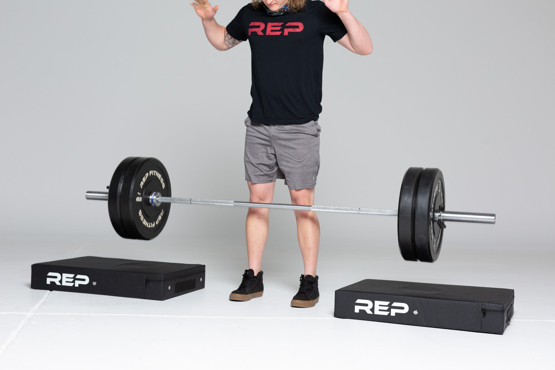 Lifter dropping a barbell loaded with two 45lb REP bumper plate pairs onto a pair of REP Crash Pads.