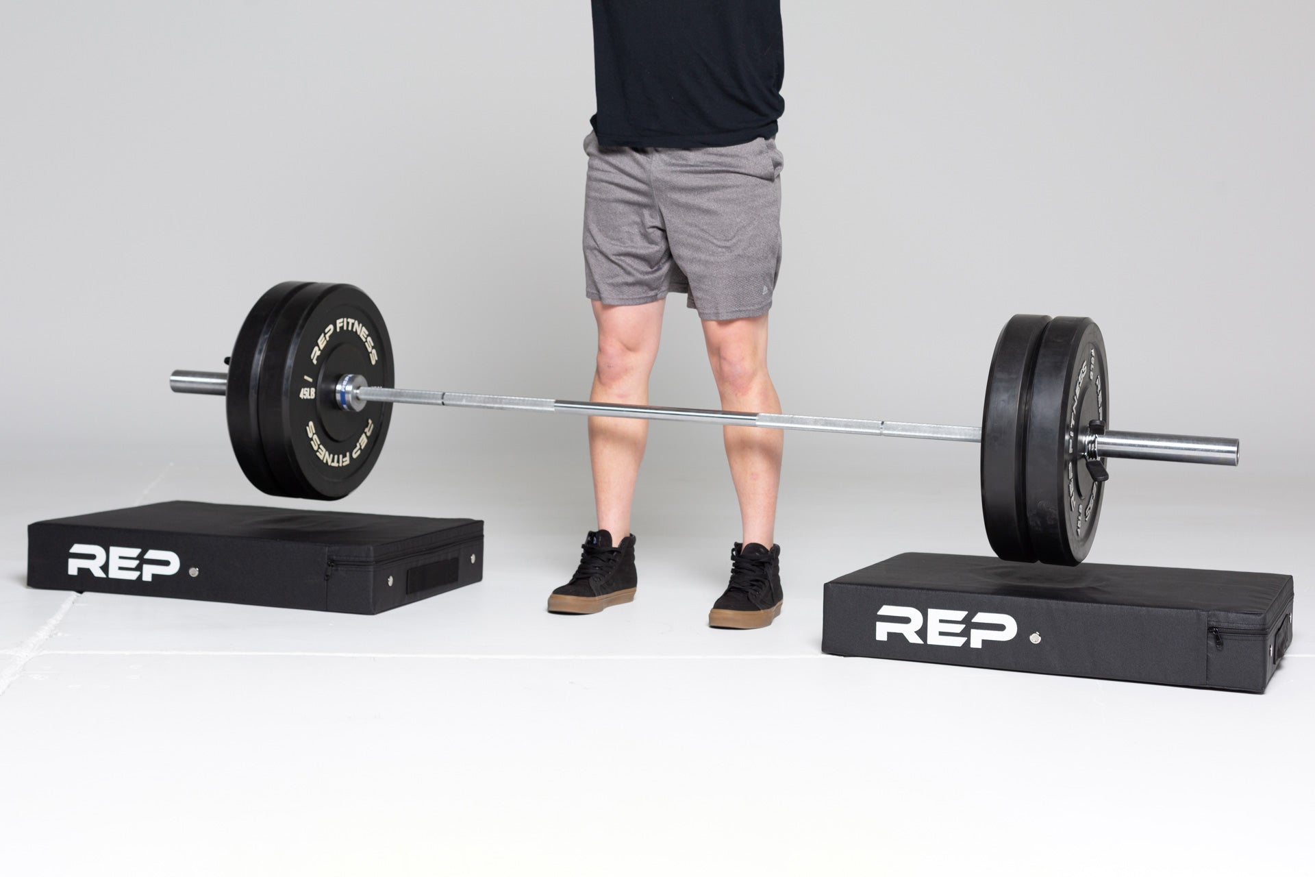 Lifter dropping a barbell loaded with two 45lb REP bumper plate pairs onto a pair of REP Crash Pads.