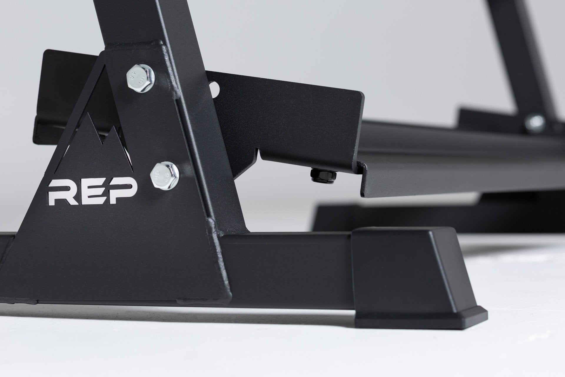 Close-up side view of the bottom of the 3-tiered matte black REP Dumbbell Rack showcasing the 